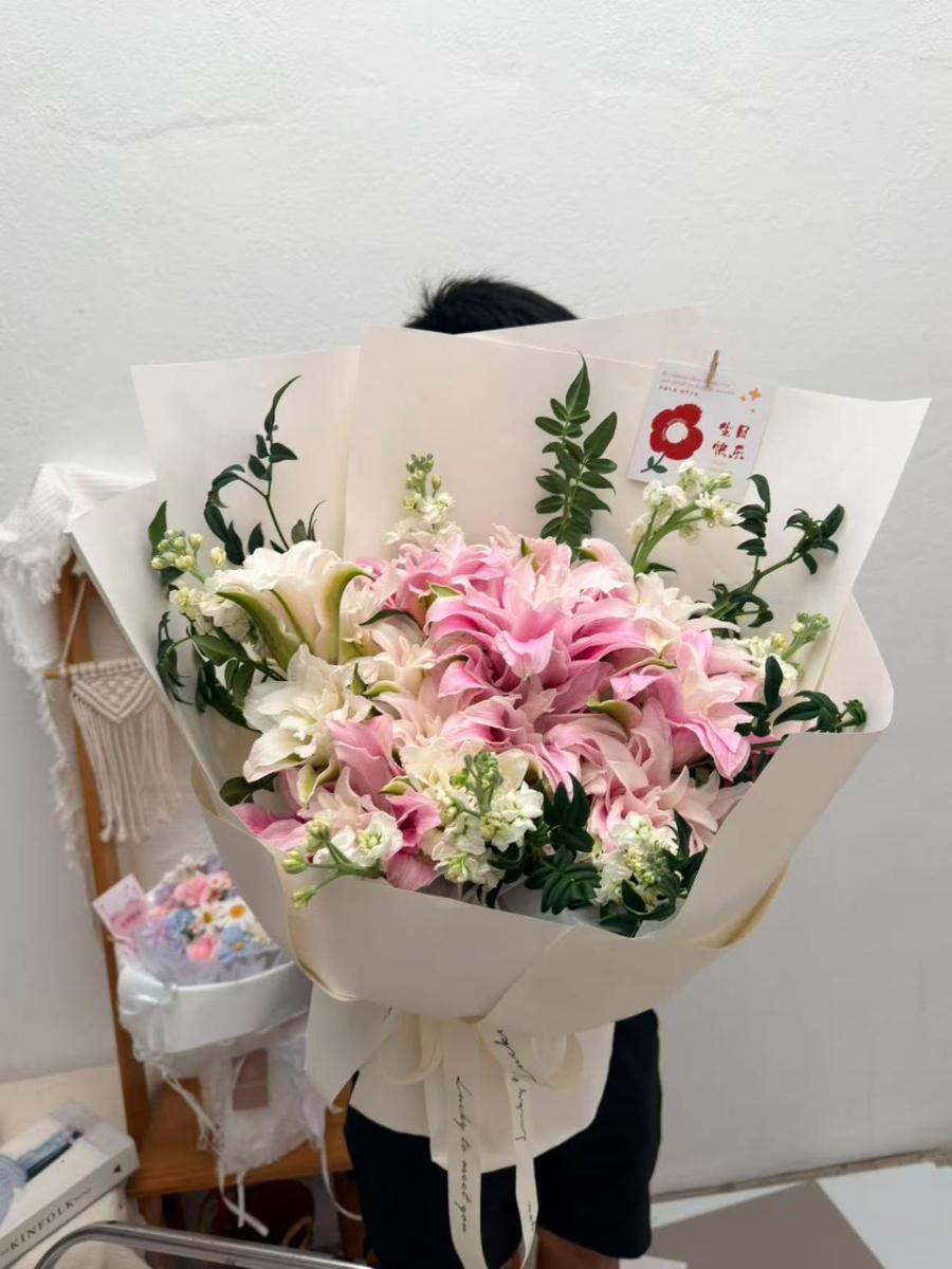 resh Mega Hand-Tied Bouquet in Textured White Packaging Featuring Abundant Pink and White Double Lilies, Small White Flowers, and Green Branches