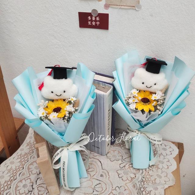 Sky Blue Wrapped Graduation Bouquet Featuring a Smiling Cloud Doll in a Graduation Cap and Sunflower
